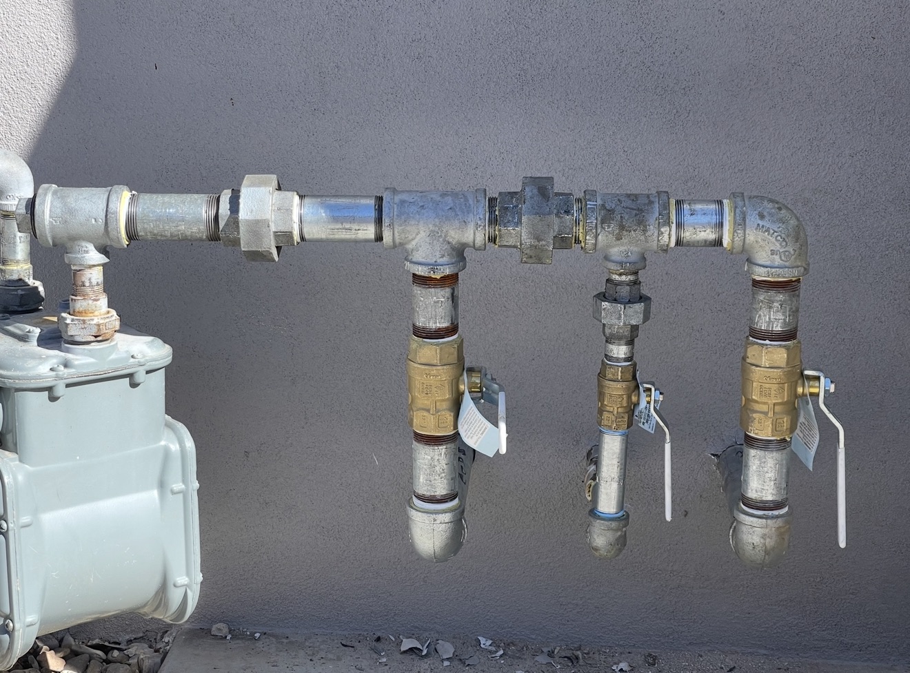 Gas meter and brass shutoff valves on a stucco wall